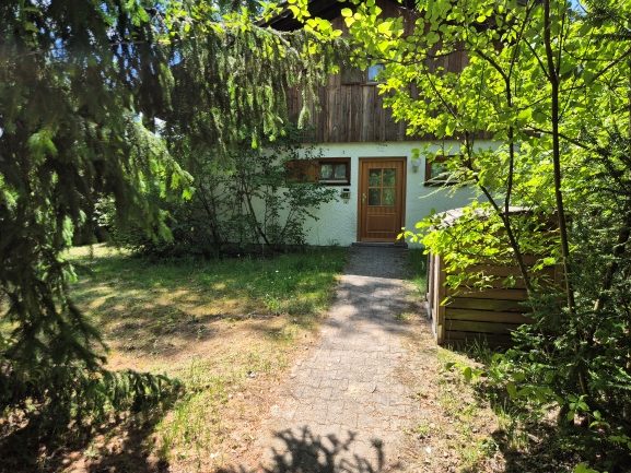 Hauseingang des Ferienhaus 22 mit gepflastertem Weg, umrahmt von frischem Grün