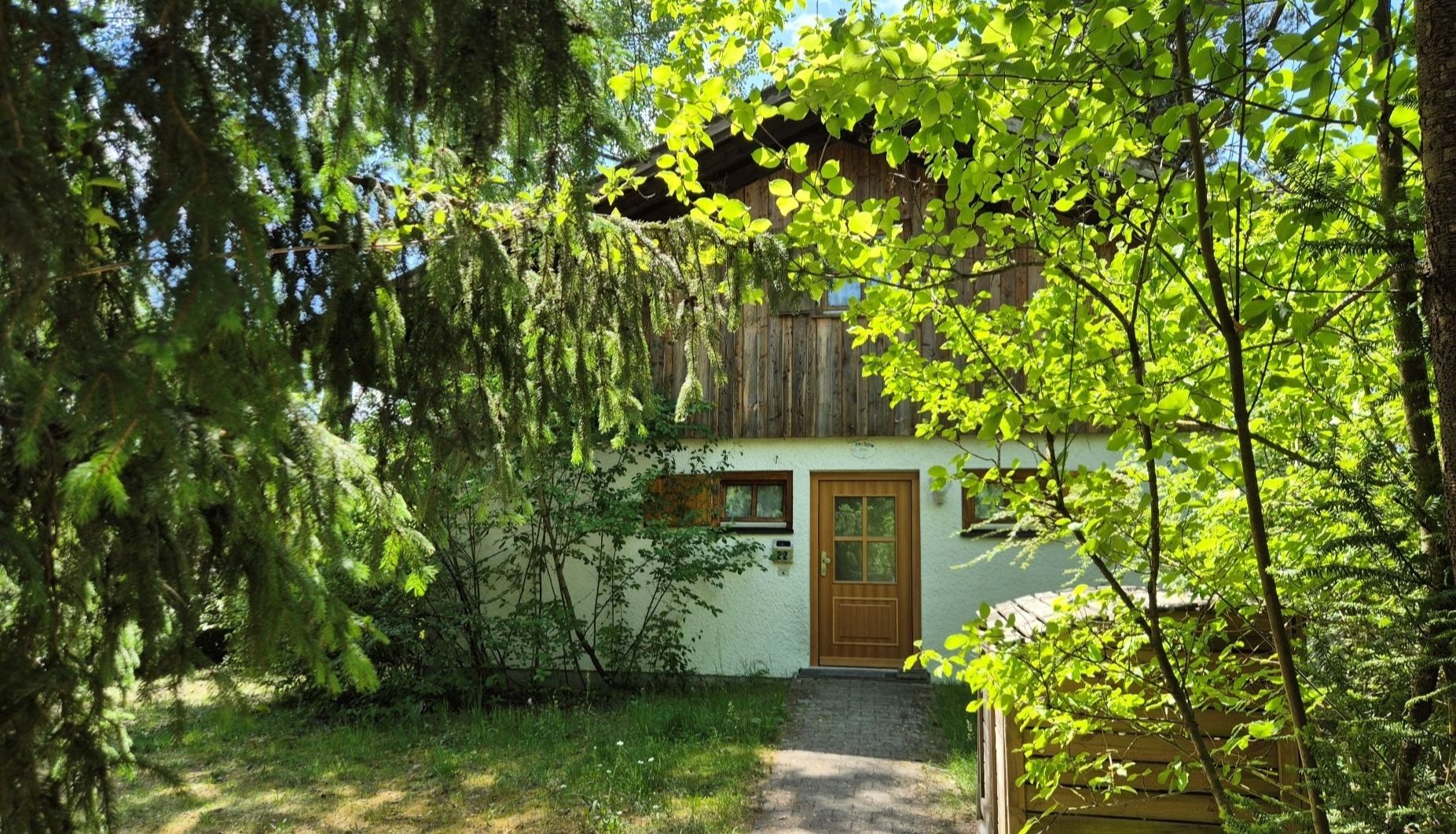 Ferienhaus 22 mit Holzgiebel, umrahmt von frischem Grün am Waldrand